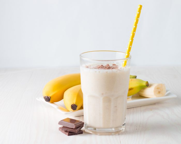 Fresh Made Chocolate Banana Smoothie on a wooden table. Selective focus. Milkshake with almonds. Protein diet. Healthy food and drink concept.