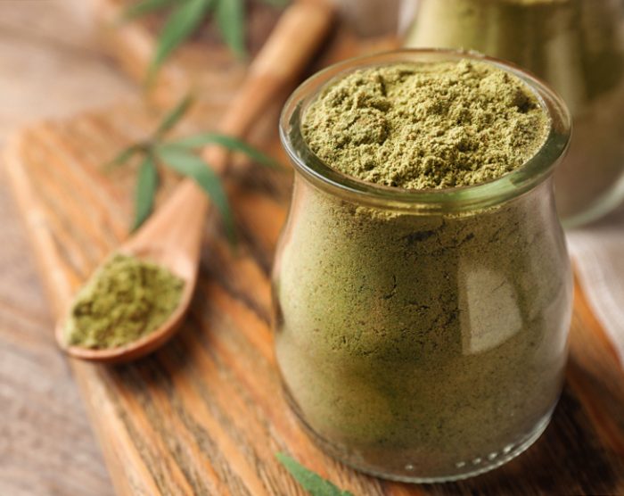 Jar of hemp protein powder on wooden table. Space for text